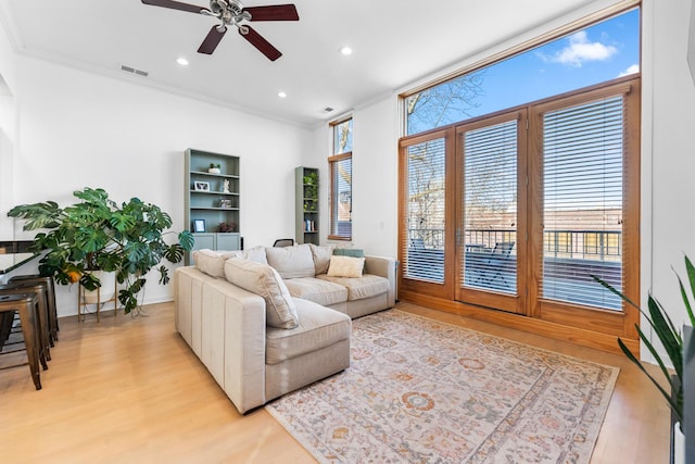 living area featuring light wood finished floors, recessed lighting, visible vents, and ornamental molding