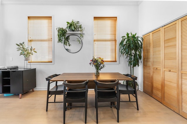 dining room featuring ornamental molding, light wood-style flooring, and baseboards