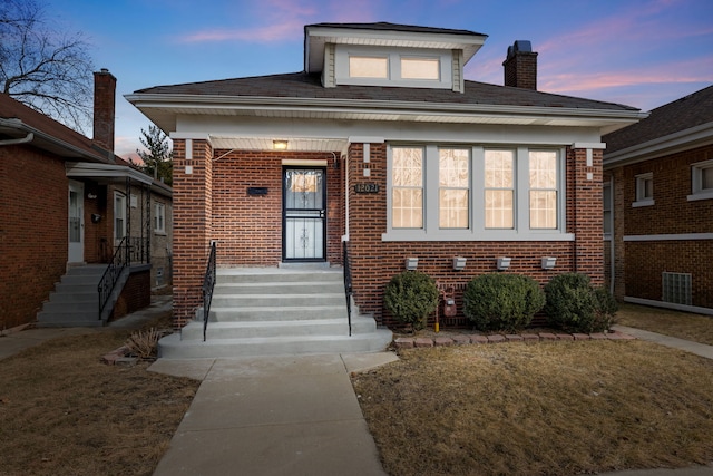 bungalow featuring a chimney and brick siding