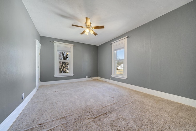 empty room with a wealth of natural light, baseboards, carpet, and a ceiling fan