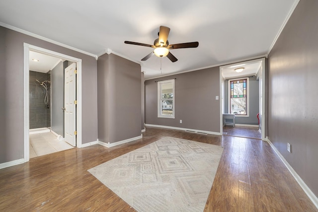 spare room featuring ornamental molding, baseboards, and wood finished floors