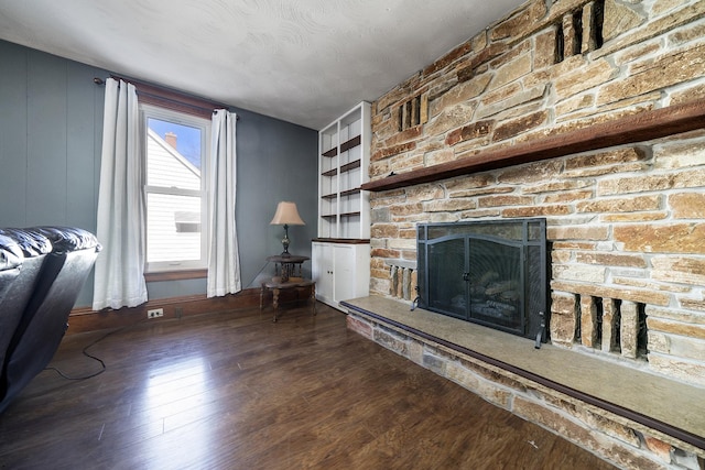 unfurnished living room featuring a stone fireplace, wood finished floors, and baseboards