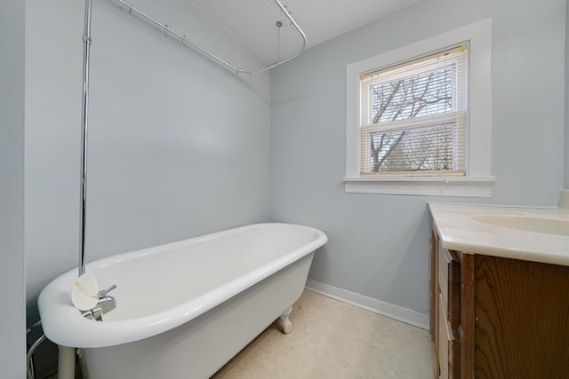 full bathroom featuring tile patterned floors, baseboards, a freestanding bath, and vanity