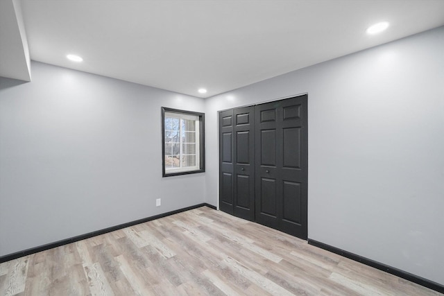 unfurnished bedroom with a closet, baseboards, wood finished floors, and recessed lighting