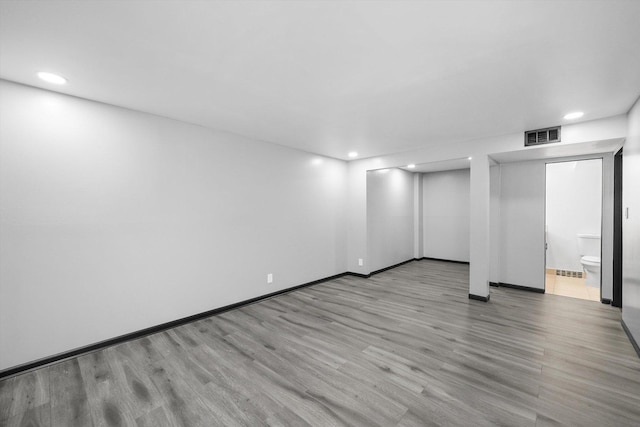 empty room with baseboards, visible vents, wood finished floors, and recessed lighting