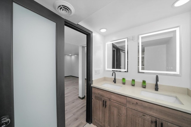 bathroom with double vanity, wood finished floors, a sink, and visible vents