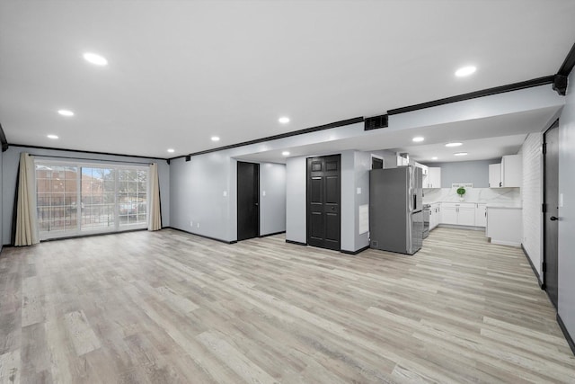 kitchen with light wood-style flooring, stainless steel refrigerator with ice dispenser, crown molding, and open floor plan