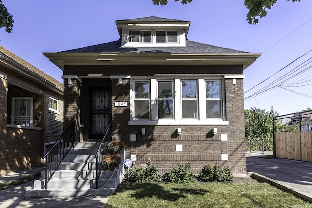 bungalow featuring brick siding and fence