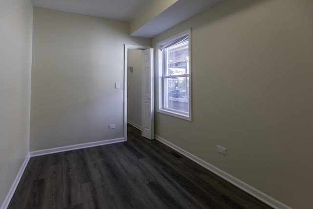 spare room featuring dark wood finished floors and baseboards