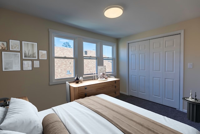 bedroom with a closet, dark carpet, and baseboards