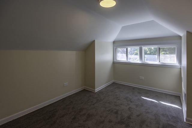 bonus room featuring vaulted ceiling, dark carpet, and baseboards