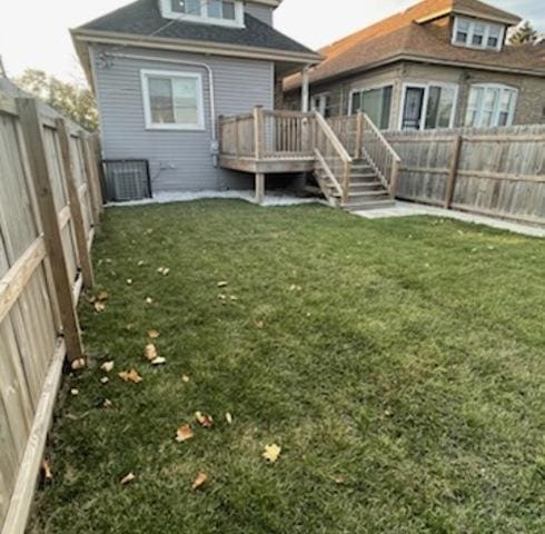 back of property featuring a fenced backyard, cooling unit, a lawn, and a wooden deck