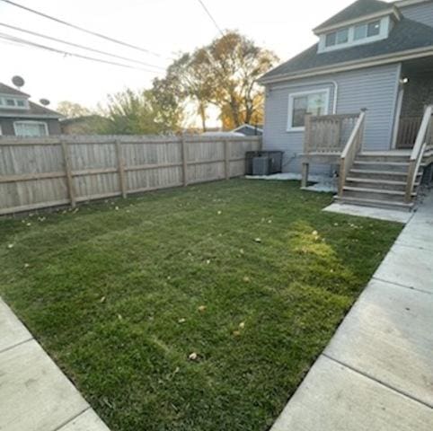 view of yard with a fenced backyard, a wooden deck, and central air condition unit