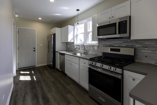 kitchen with dark wood-style flooring, backsplash, appliances with stainless steel finishes, white cabinets, and a sink