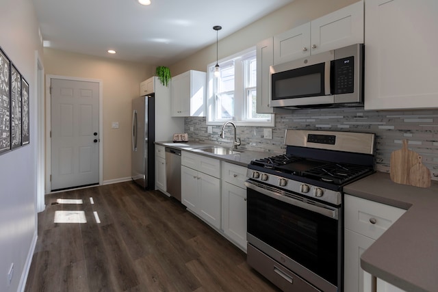 kitchen featuring stainless steel appliances, white cabinets, a sink, and dark wood-style floors