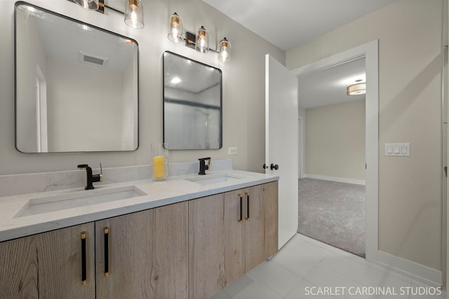 bathroom featuring double vanity, a sink, visible vents, and baseboards