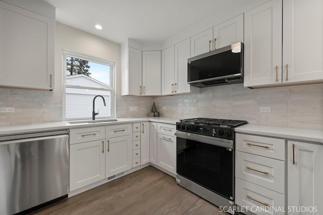 kitchen with wood finished floors, a sink, white cabinets, range with gas stovetop, and dishwasher