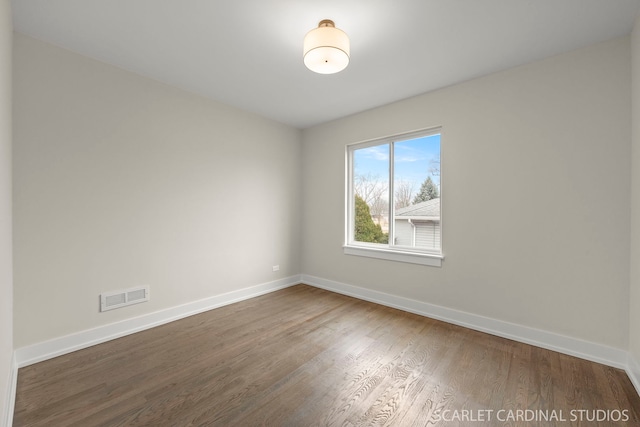 spare room featuring dark wood-style floors, visible vents, and baseboards