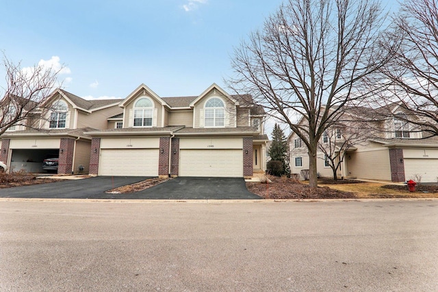 view of front of house featuring a garage, brick siding, driveway, and a shingled roof