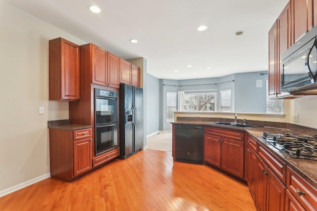 kitchen featuring recessed lighting, a sink, light wood-type flooring, a peninsula, and black appliances