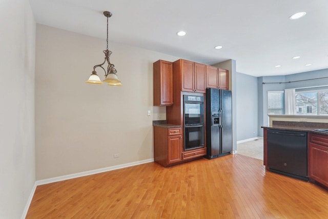 kitchen featuring baseboards, black appliances, light wood finished floors, dark countertops, and pendant lighting