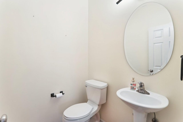 bathroom with a sink, toilet, and baseboards