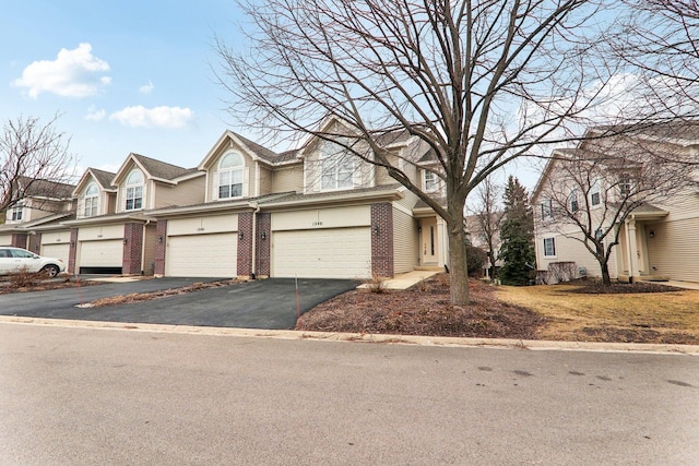 townhome / multi-family property featuring driveway, a garage, and brick siding