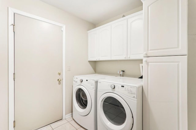 laundry area with light tile patterned floors, baseboards, cabinet space, and washer and dryer