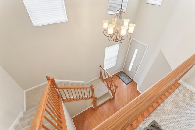 entryway with stairway, wood finished floors, a towering ceiling, and baseboards