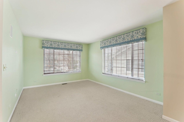 spare room with carpet, a healthy amount of sunlight, and baseboards