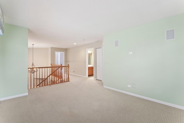 unfurnished room featuring a chandelier, light carpet, visible vents, and baseboards