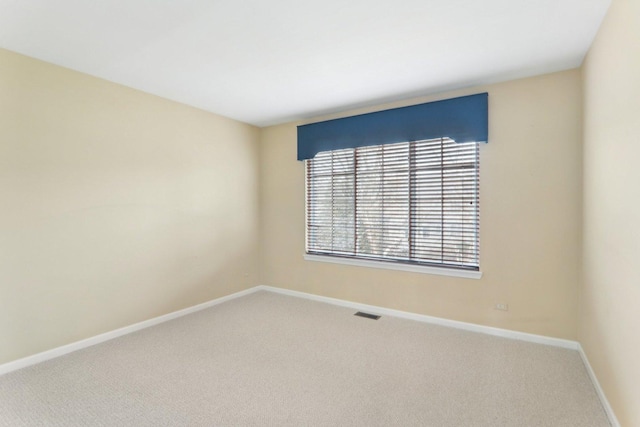 empty room featuring carpet flooring, visible vents, and baseboards