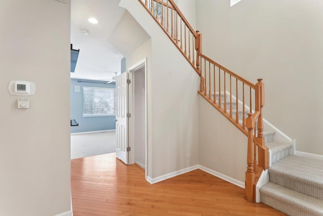 staircase featuring wood-type flooring, baseboards, and recessed lighting