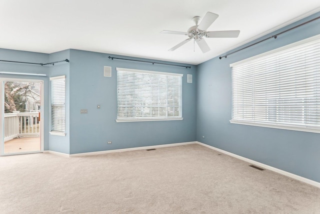 carpeted spare room featuring a ceiling fan, visible vents, and baseboards