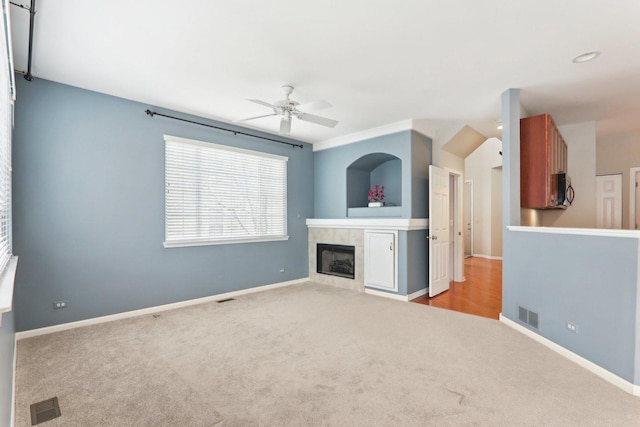 unfurnished living room featuring carpet, a fireplace, visible vents, and baseboards