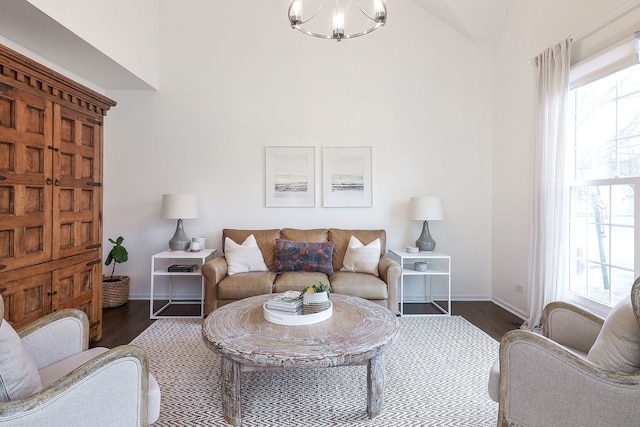 living room with a chandelier, baseboards, and wood finished floors