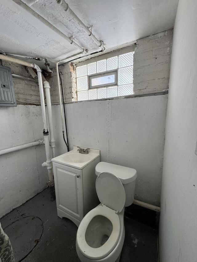 bathroom featuring electric panel, unfinished concrete flooring, vanity, and toilet