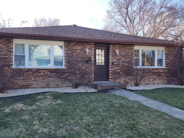 single story home with a shingled roof, brick siding, and a front lawn