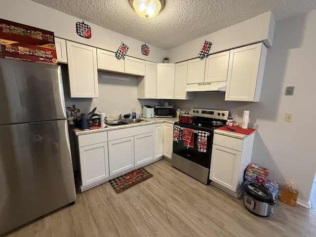 kitchen featuring under cabinet range hood, stainless steel appliances, a sink, white cabinetry, and light wood-style floors