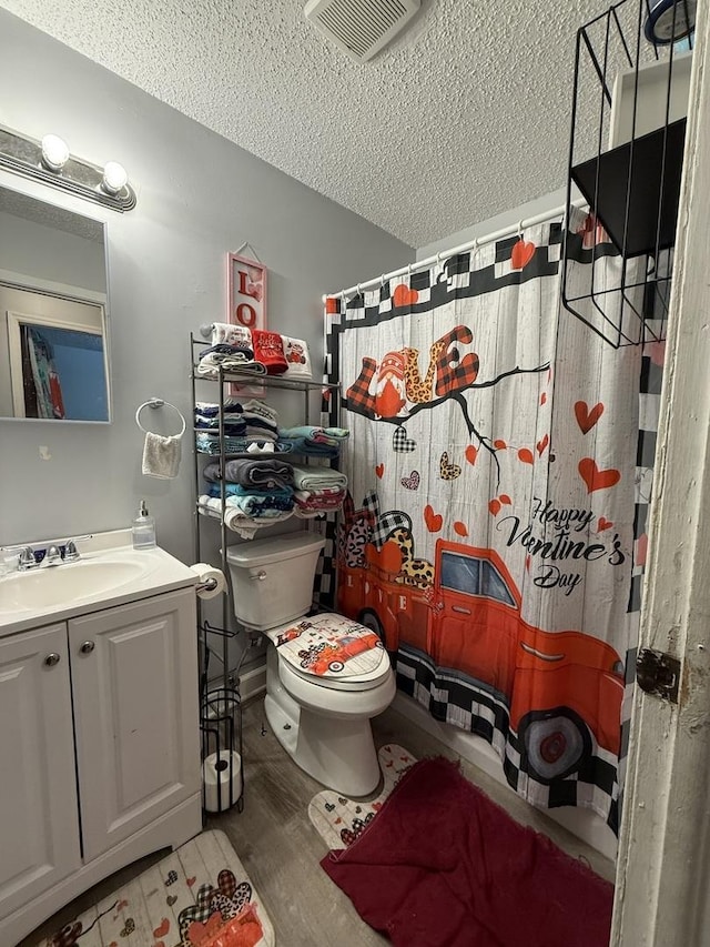 full bathroom with a textured ceiling, toilet, wood finished floors, vanity, and visible vents