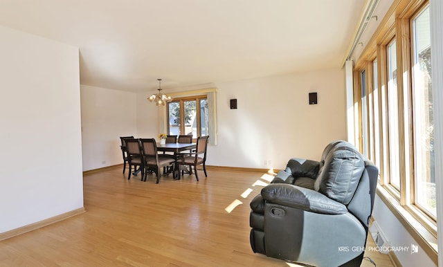 dining room featuring baseboards, a notable chandelier, and light wood finished floors