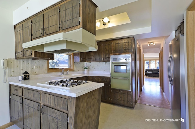 kitchen with white appliances, extractor fan, light countertops, a warming drawer, and backsplash