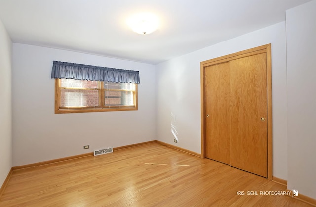 unfurnished bedroom with light wood-type flooring, visible vents, baseboards, and a closet