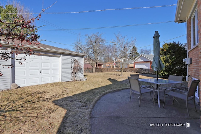 view of yard with a garage, an outdoor structure, outdoor dining space, and a patio area