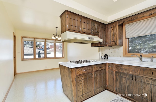 kitchen featuring white gas cooktop, under cabinet range hood, a sink, baseboards, and light floors