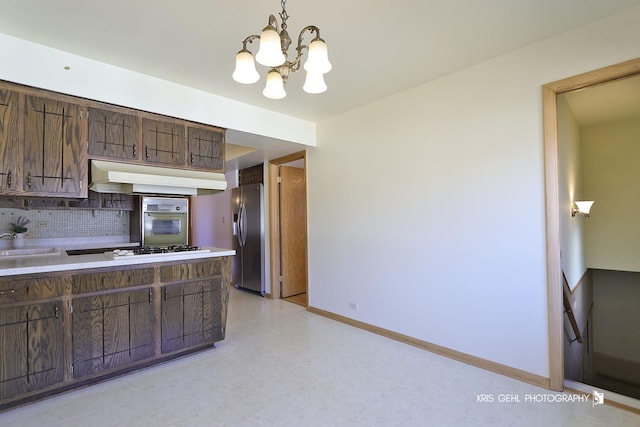 kitchen featuring backsplash, baseboards, extractor fan, white gas cooktop, and stainless steel fridge