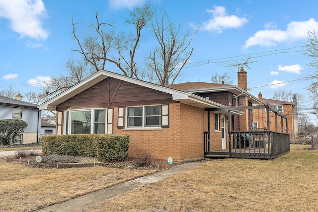 view of front of house featuring a wooden deck, a chimney, a front lawn, and brick siding