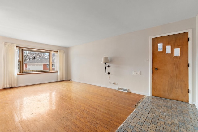 unfurnished living room featuring baseboards, visible vents, and wood finished floors