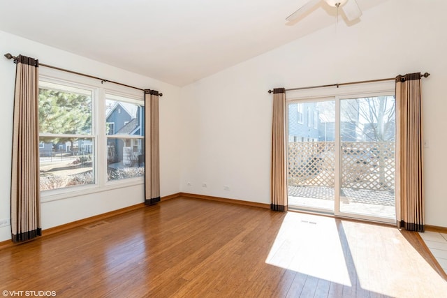 unfurnished room featuring lofted ceiling, plenty of natural light, wood finished floors, and visible vents