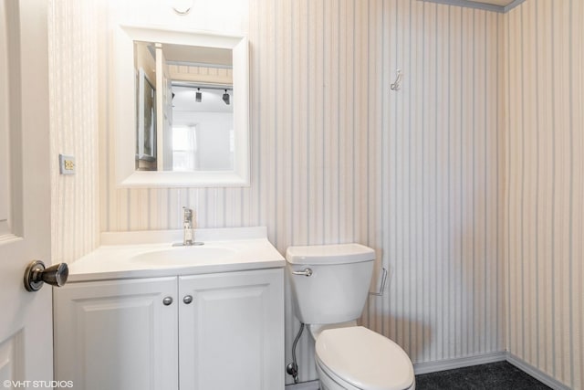 half bath featuring toilet, wallpapered walls, and vanity